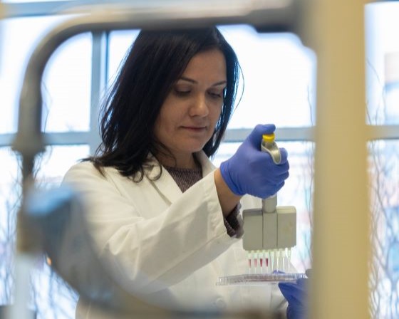 student researcher transfers liquid in the dental lab