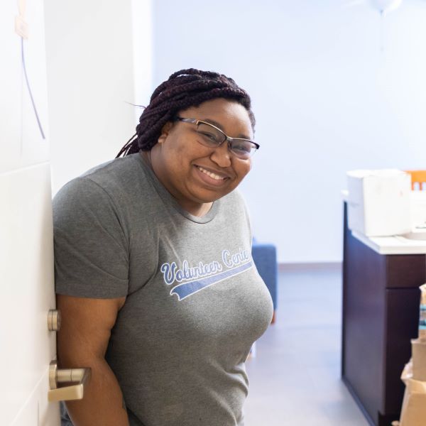 a student stands at the door of her apartment on the 威尼斯人娱乐城 Hospital Hill campus. There are cardboard moving boxes stacked behind her.