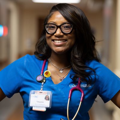 塔季扬娜查尔斯 wears scrubs and has a stehoscope around her neck