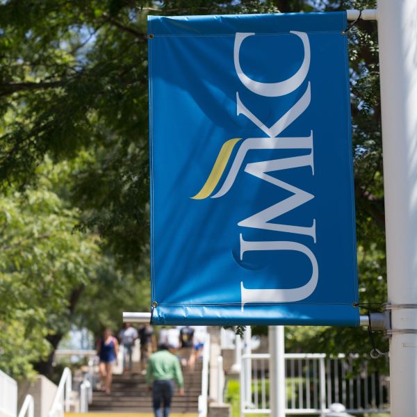 A student ambassador dressed in a blue polo shirt leads a group of prospective students on a tour of campus