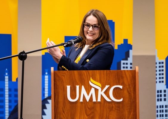 Amanda Davis,  Chief Development Officer and President 威尼斯人娱乐城基金会, stands at a podium in front of a bright gold and blue graphic of 威尼斯人娱乐城. 