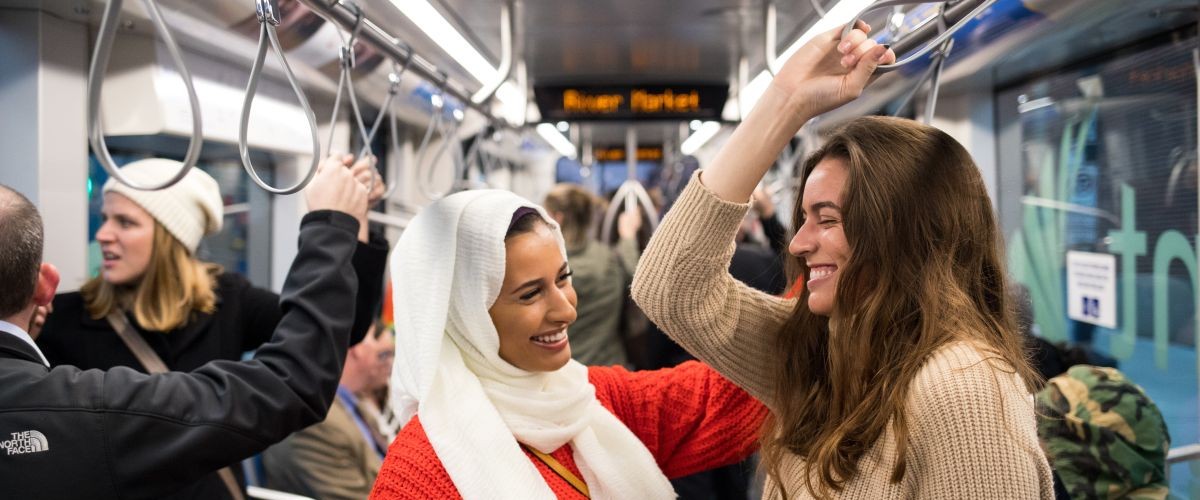 Two students stand while riding the streetcar to the River Market
