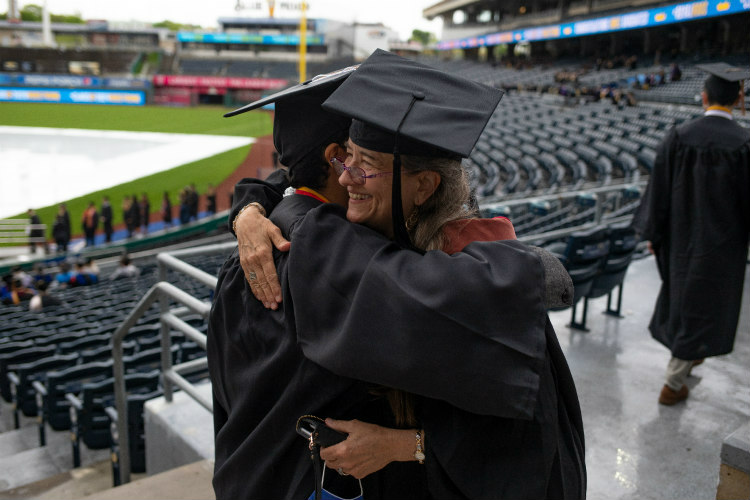 Two people in regalia hugging