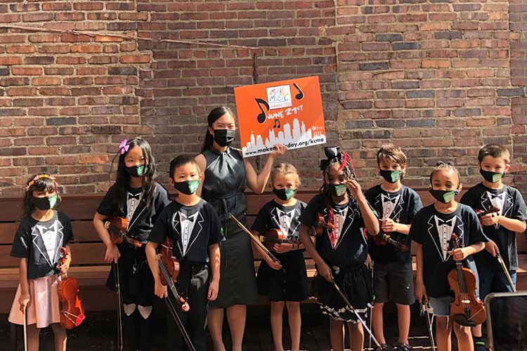 En-Ting with her class holding a "Make Music Day" sign
