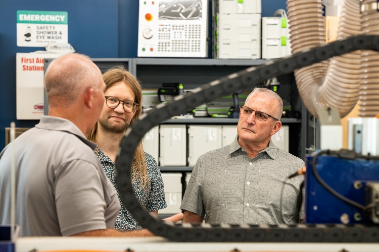 Iain Blair and Bill Yord face John Kevern as the three speak inside the Plaster Center with equipment surrounding them.