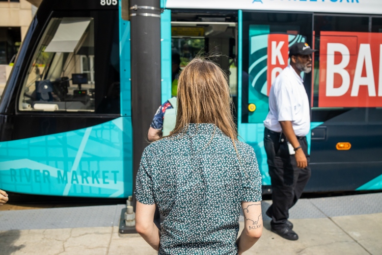 Iain Blair faces the KC Streetcar with his back to the camera as the doors of the streetcar open.