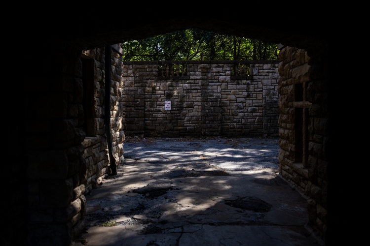 A stone, exterior courtyard shaded by trees