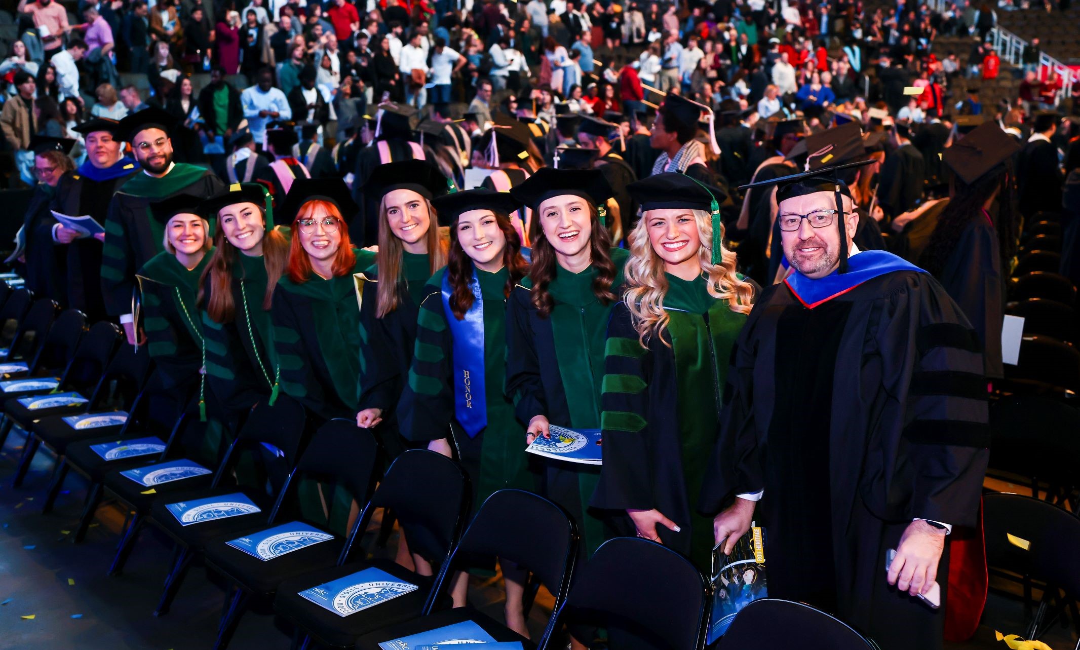 School of Medicine St. Joseph graduates in a line at their seats during the ceremony, smiling for a photo
