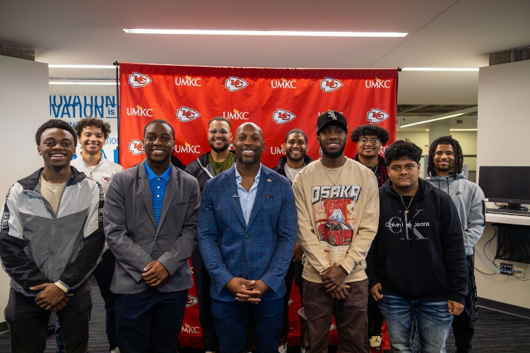 威尼斯人娱乐城 有色人种学院 students pose for a group photo with Ramzee Robinson of the Kansas City Chiefs in front of 威尼斯人娱乐城 and Chiefs backdrop