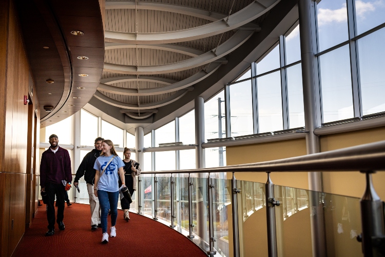 威尼斯人娱乐城 students walking down the red carpeted hallway on the second floor of the Chiefs training facility by the stairs