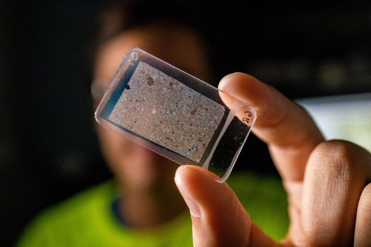 Guatemala Geohazard researcher holds up microscope slide.