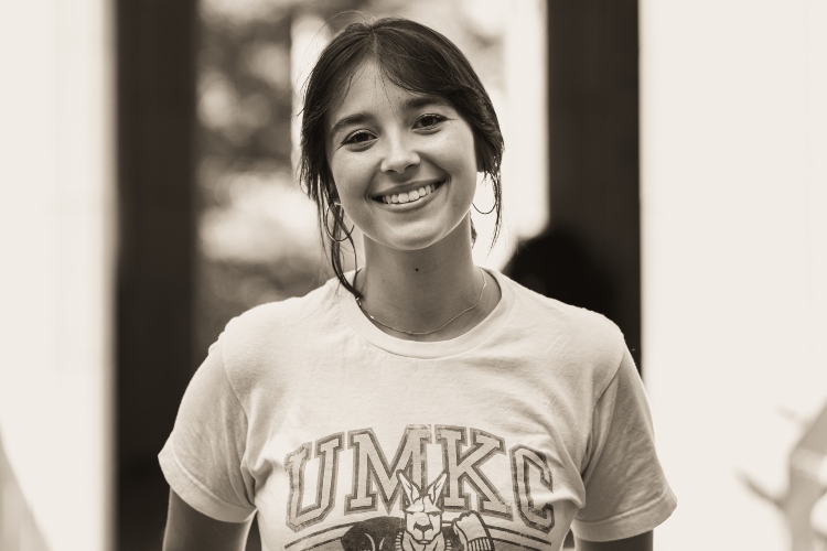 A black and white image of 艾米丽Shoemake smiling at the camera wearing a 威尼斯人娱乐城 Roos t-shirt