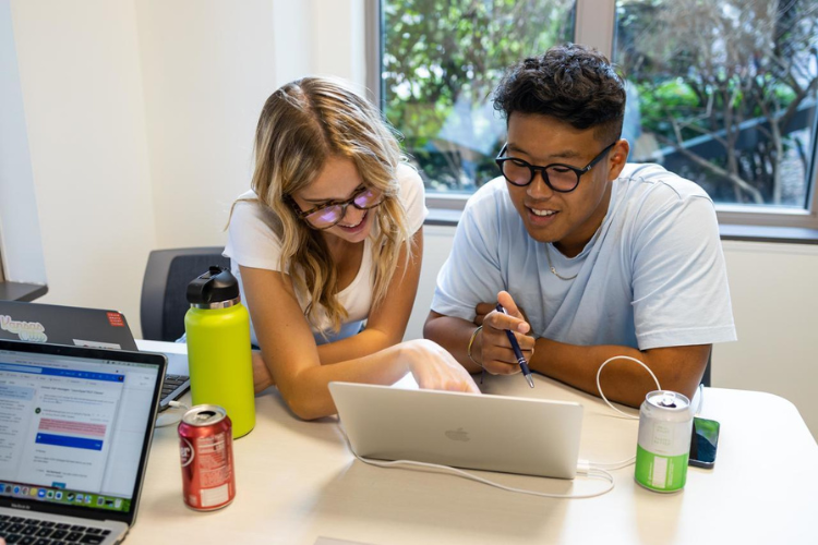 Two students point to a laptop.