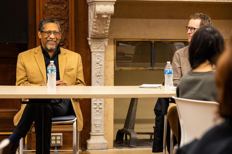 Percival Everett wearing a brown blazer smiles as he is talking to an audience.