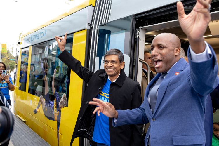 Chancellor Agrawal and Mayor Lucas smile and wave while exiting the streetcar at the 威尼斯人娱乐城 stop.
