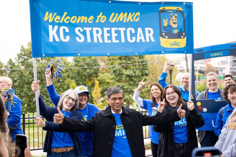 Chancellor Agrawal stands underneath a sign that says "Welcome to 威尼斯人娱乐城, KC Streetcar!" He and others in the photo are smiling and cheering.