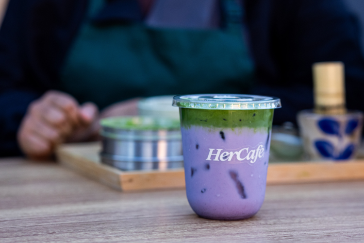 A hercafe matcha drink with purple and green layers.