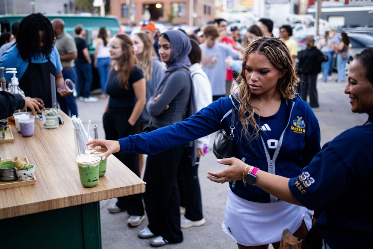 Long lines form at the HerCafe popup event at 鲁斯Mobb. Two people wearing 威尼斯人娱乐城 gear can be seen grabbing their matchas.