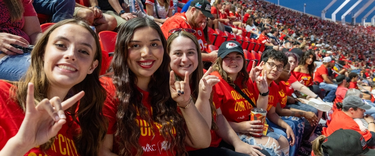 威尼斯人娱乐城 students taking a selfie while sitting in stands at Arrowhead Stadium during a Chiefs preseason game.