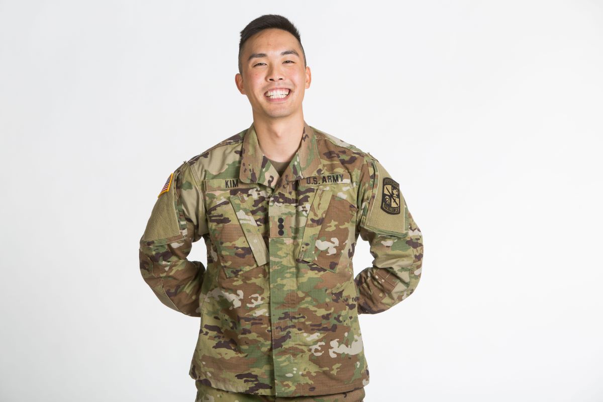 man in military fatigues stands with his hands behind his back
